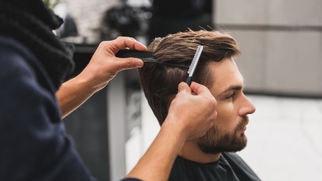 Barbeiro cortando o cabelo masculino antes de descolorir para o cabelo platinado masculino.