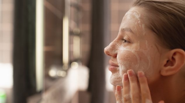 Mulher com bem cuidada e sem marcas lavando o rosto com sabonete de rosto, fazendo sua limpeza facial com vitamina c.