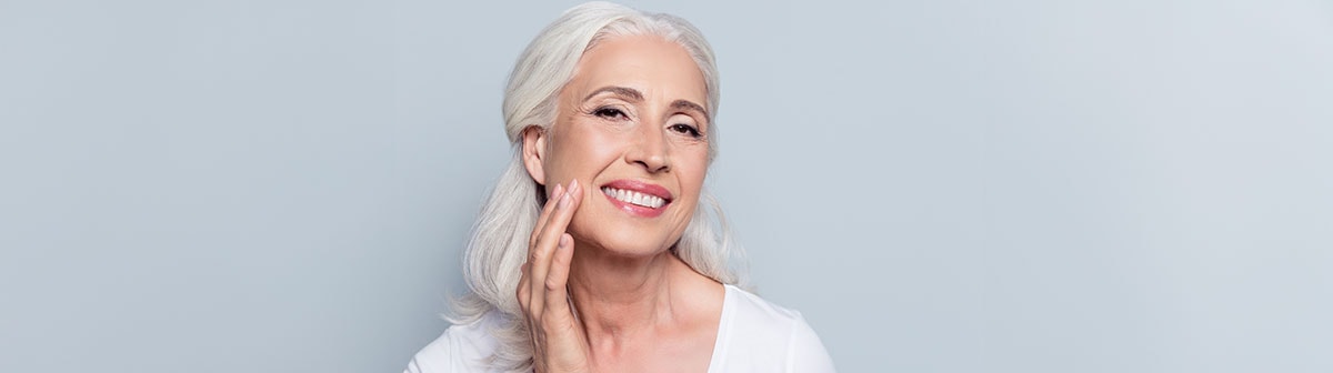 Senhora toca a pele sem manchas do seu rosto suavemente enquanto sorri