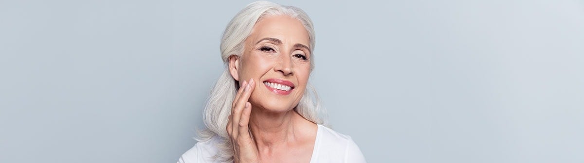 Senhora toca a pele sem manchas do seu rosto suavemente enquanto sorri