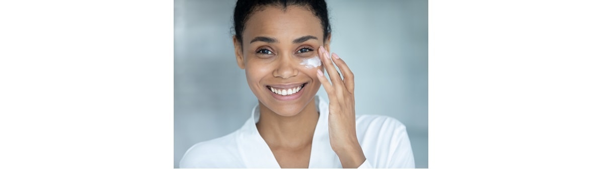 Mulher negra aplica creme com colágeno na pele para manter a pele de seu rosto jovem