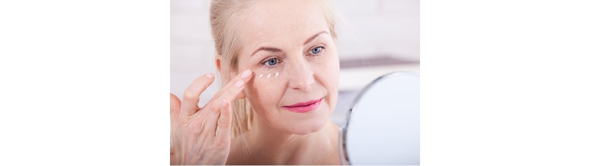 Senhora caucasiana utiliza creme antissinais e anti-idade em seu rosto para cuidar da pele facial.