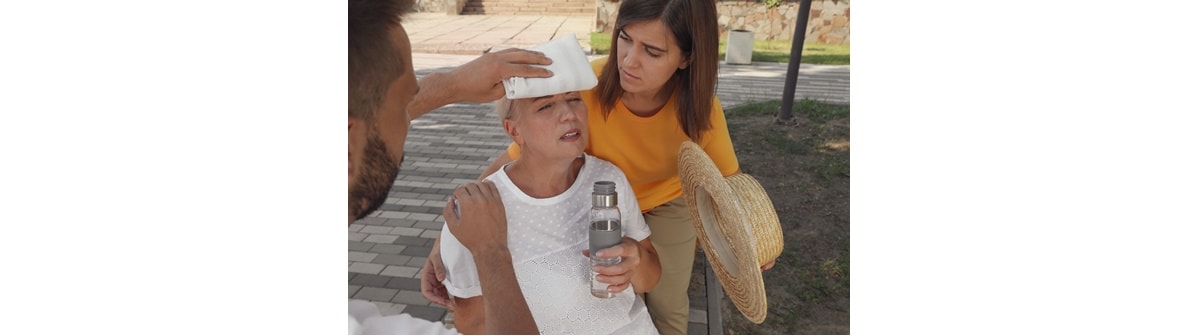 Mulher sofre de insolação nas ruas de sua cidade e é socorrida por pessoas próximas.