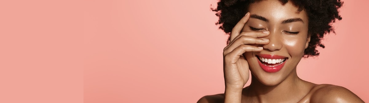 Mulher negra sorri ao tocar sua pele perfeita, brilhante e hidratada