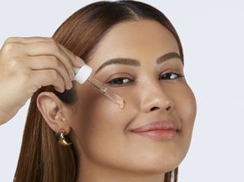 Mulher aplicando sérum no rosto com conta-gotas