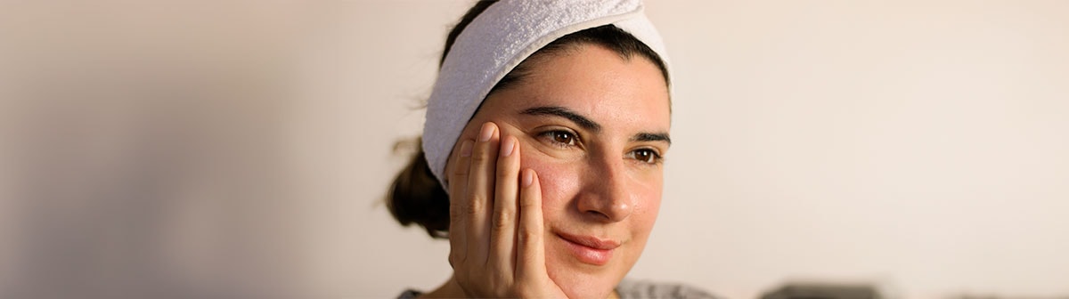 mulher de pele clara com faixa na cabeça com a mão apoiada no rosto