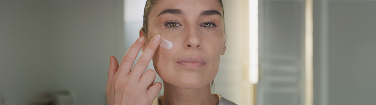 mulher de pele clara madura aplicando creme facial no rosto