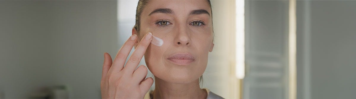 mulher de pele clara madura aplicando creme facial no rosto