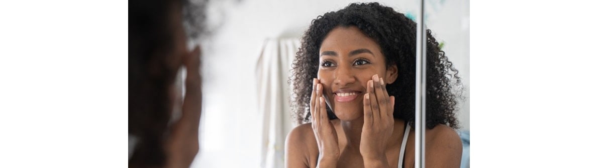 garota negra utiliza protetor solar com cor na pele do rosto