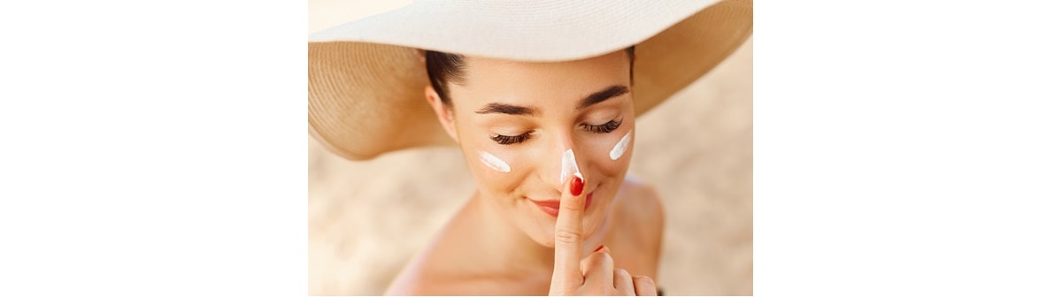 Mulher aplica protetor solar facial no rosto ao conhecer os mitos e verdades sobre o protetor solar para o rosto