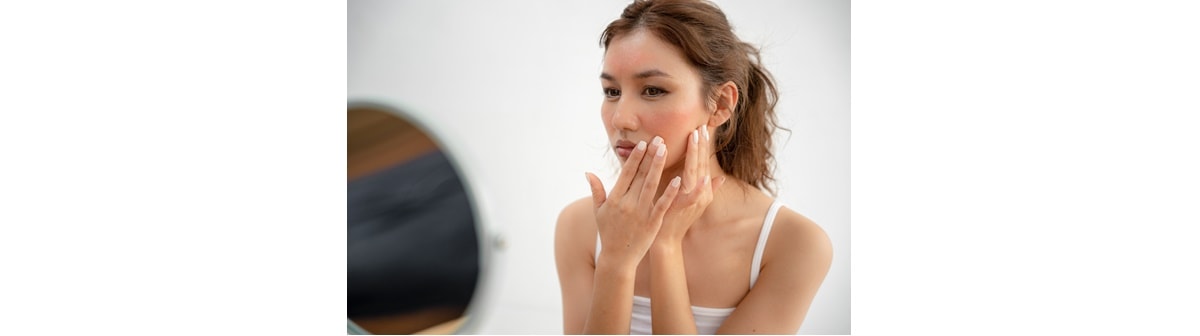 mulher observando sua pele sensível no espelho