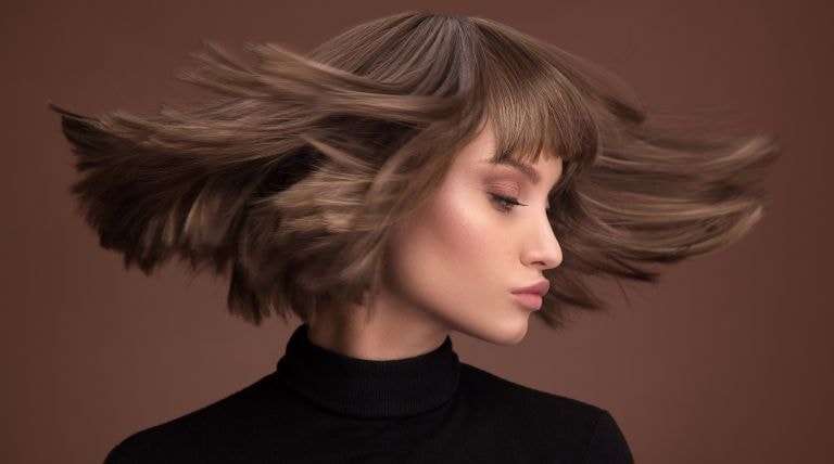 Modelo com o cabelo de cor mocha mousse em fundo marrom