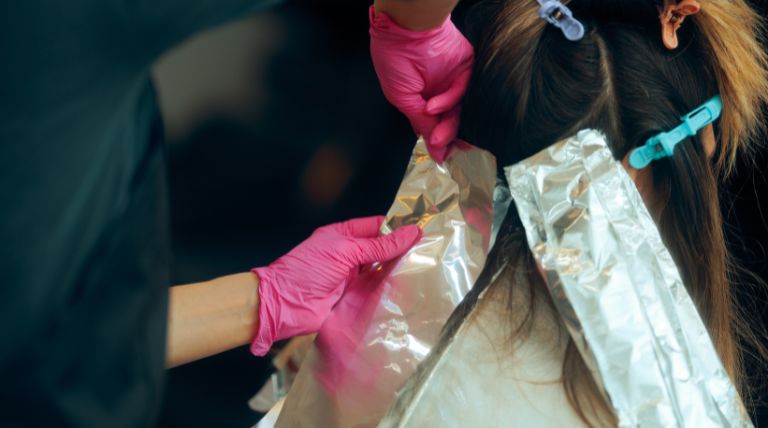 Profissional faz a técnica de morena iluminada em sua cliente no salão de beleza