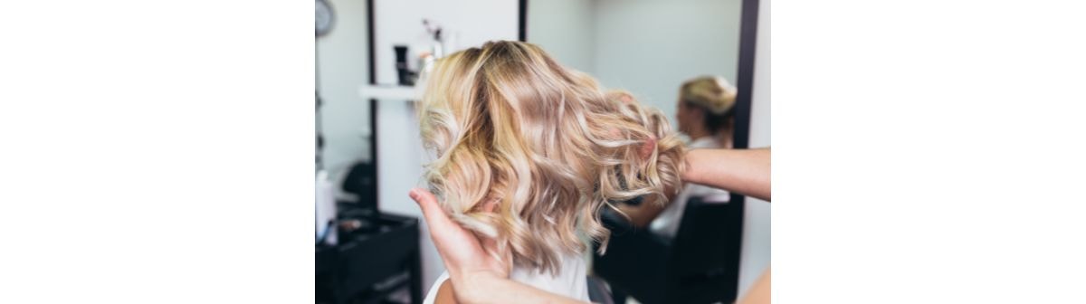 Cabelo ondulado e médio de uma mulher com a cor de cabelo loiro dourado.