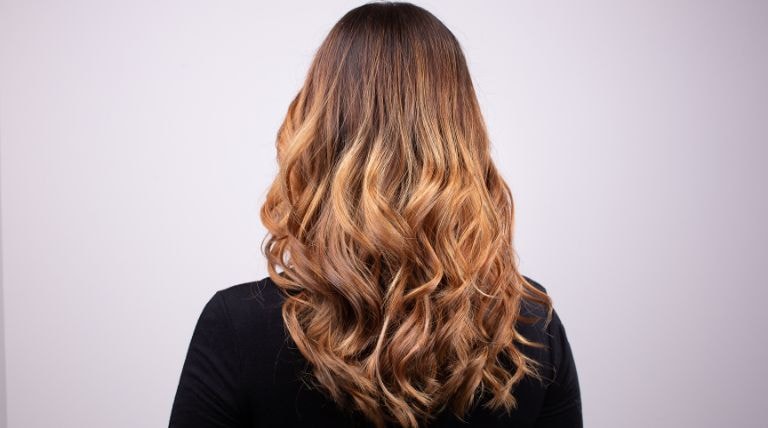 Visão traseira do cabelo loiro iluminado mel de uma mulher