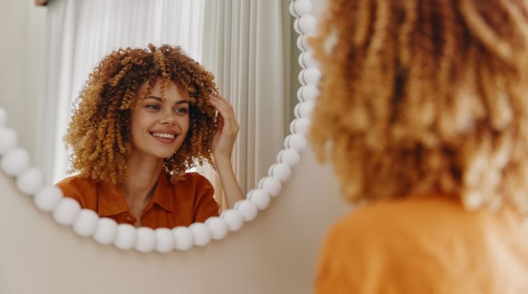 Jovem sorridente com o cabelo crespo de cor loiro iluminado mel