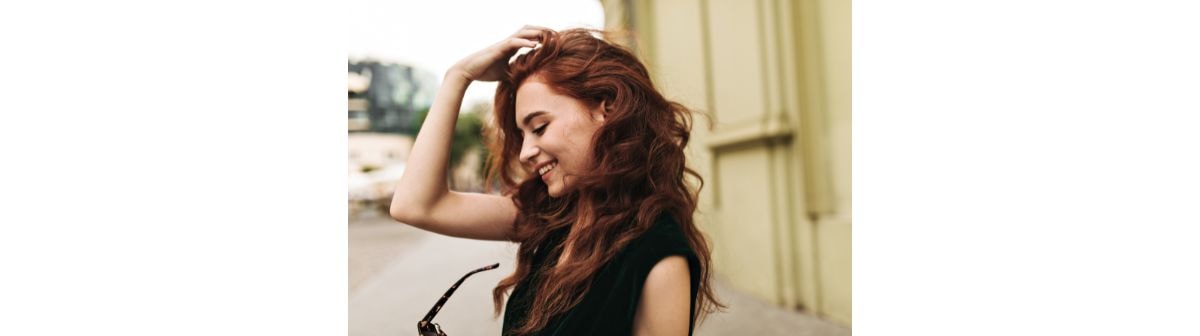 Jovem com o cabelo ondulado com a cor da tendência cowboy copper