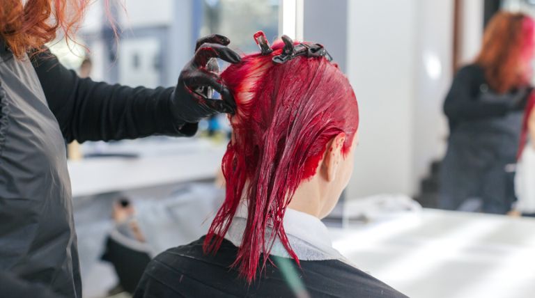 Colorista profissional aplica a coloração de cor vermelho borgonha no cabelo de sua cliente