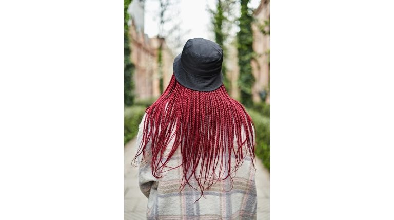 Mulher negra com um chapéu e tranças vermelho borgonha