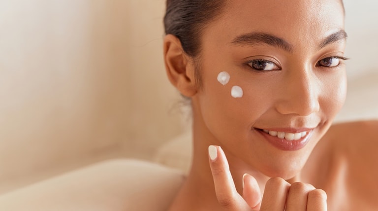 Jovem aplica hidratante com ácido hialurônico em sua pele facial