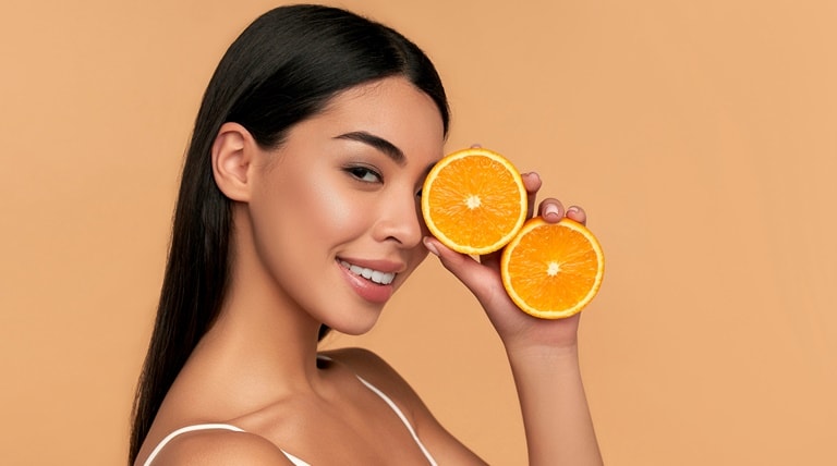 Mulher com a pele bonita e radiante mostra alimentos com vitamina c