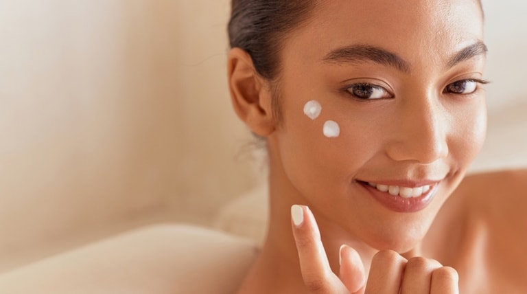 Jovem aplica hidratante com ácido hialurônico em sua pele facial