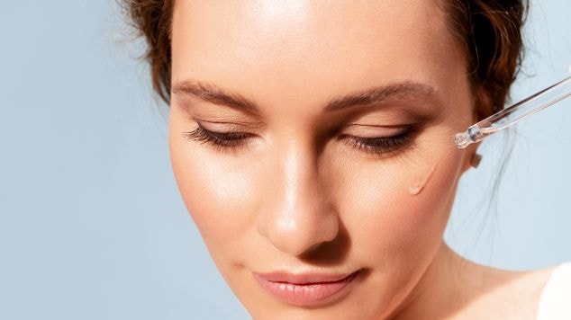 Jovem mulher aplica um sérum facial com ácido para o rosto