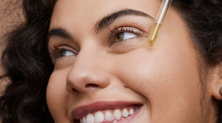 Jovem caucasiana aplica um sérum facial para tirar manchas na pele