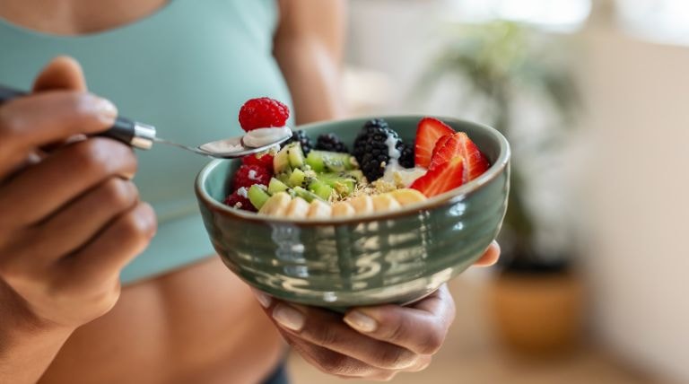 Mulher comendo frutas como parte de sua alimentação saudável para tirar espinhas