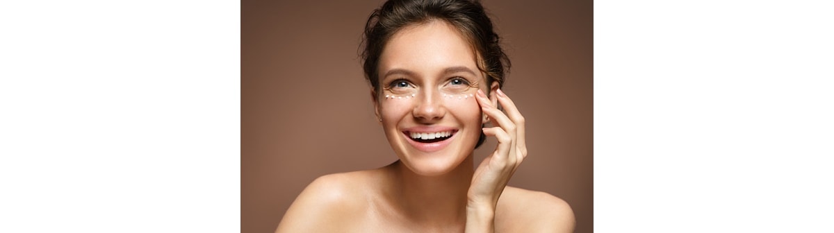 Mulher aplica creme para a área dos olhos