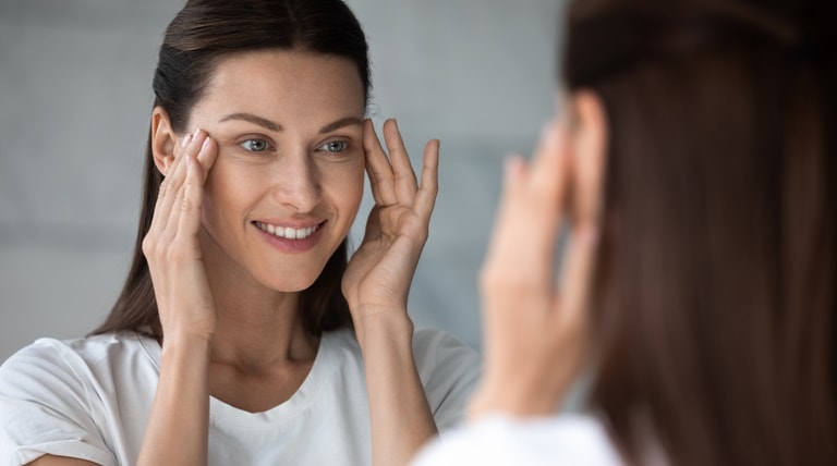 Mulher massageia a região dos olhos com creme para área dos olhos