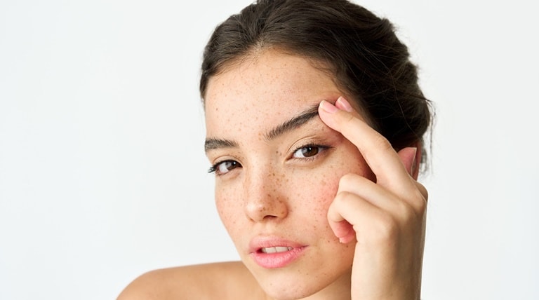 Jovem aplica creme facial e creme para os olhos para firmar sua pele facial