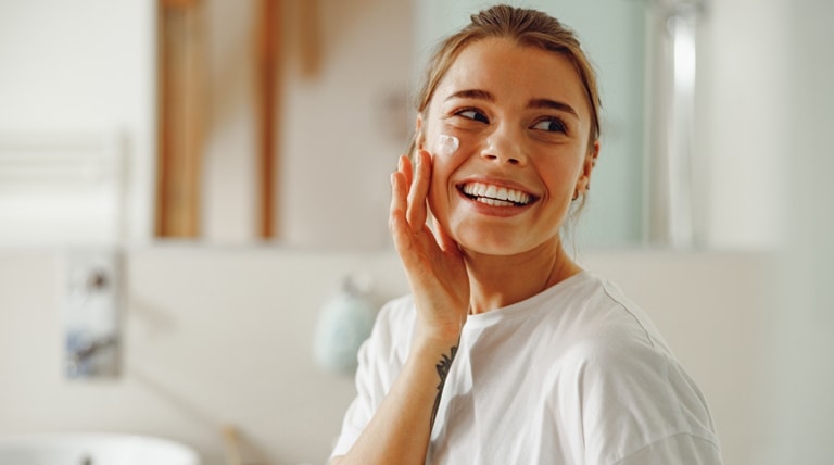 Jovem utiliza hidratante facial na pele, essencial para a beleza feminina