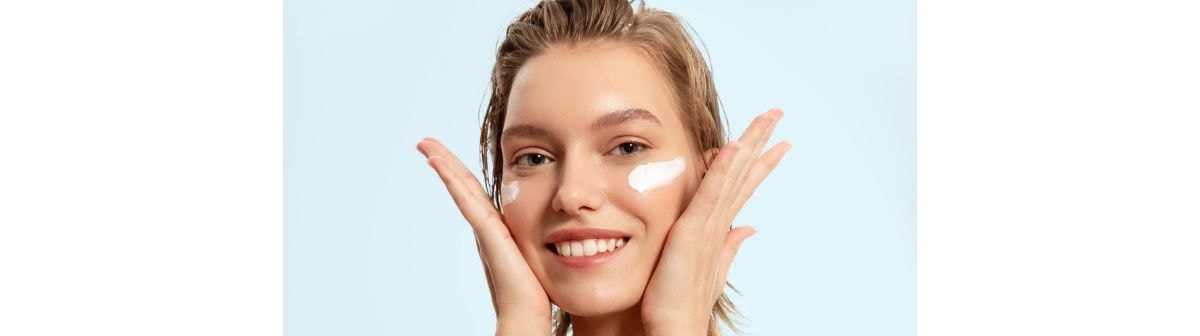 Jovem caucasiana aplica hidratante com emoliente em sua pele do rosto