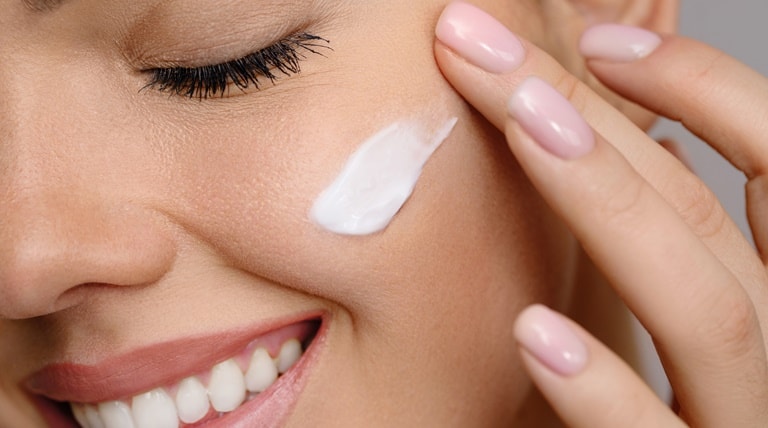 Mulher aplica hidratante facial após a esfoliação do rosto