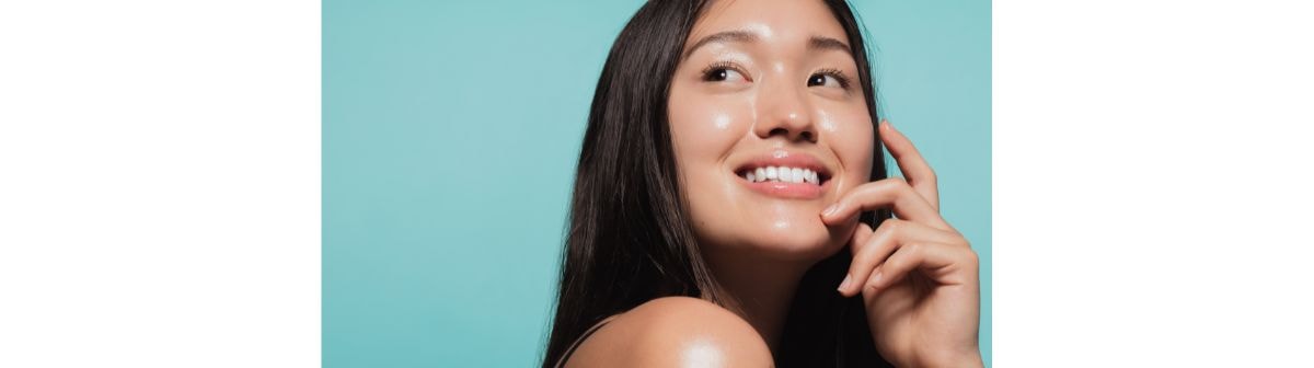 Jovem asiática feliz com a pele radiante ao usar produtos com glicerina para a pele.