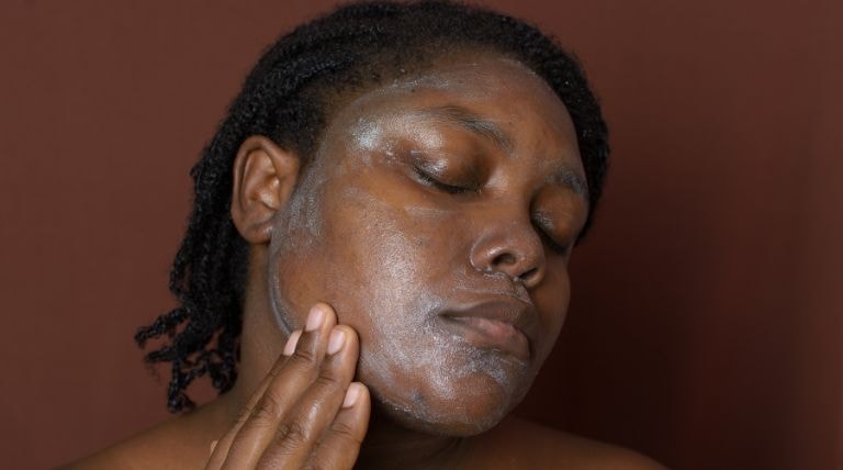 mulher com pele negra passando produtos garnier para tratamento de hiperpigmentação