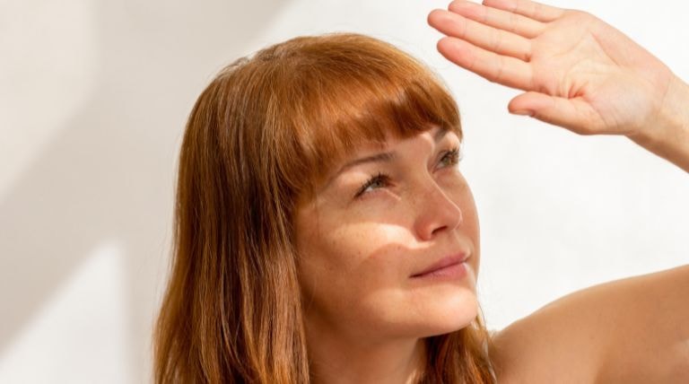 Mulher caucasiana esconde a pele do sol para evitar manchas brancas no rosto