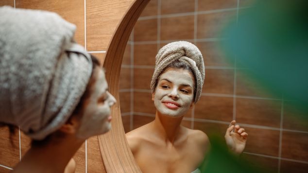 Jovem com máscara facial no rosto realiza a técnica de morning shed durante a rotina de skincare noturno