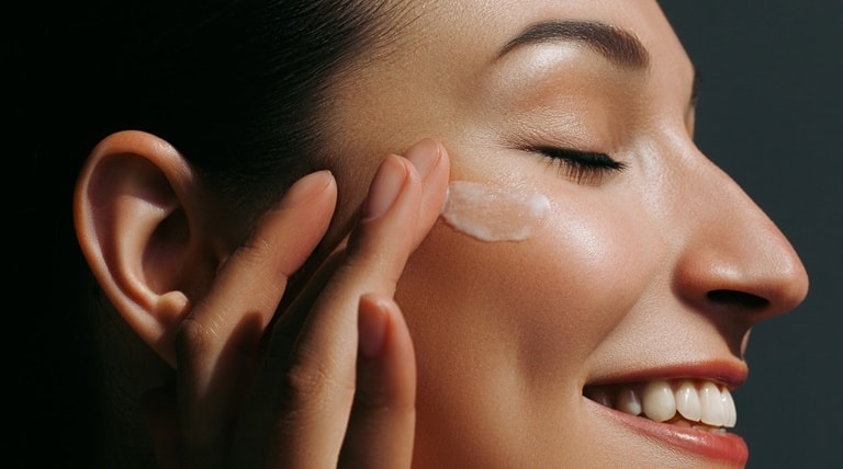 Jovem mulher aplica nicotinamida com outros ativos em sua pele facial