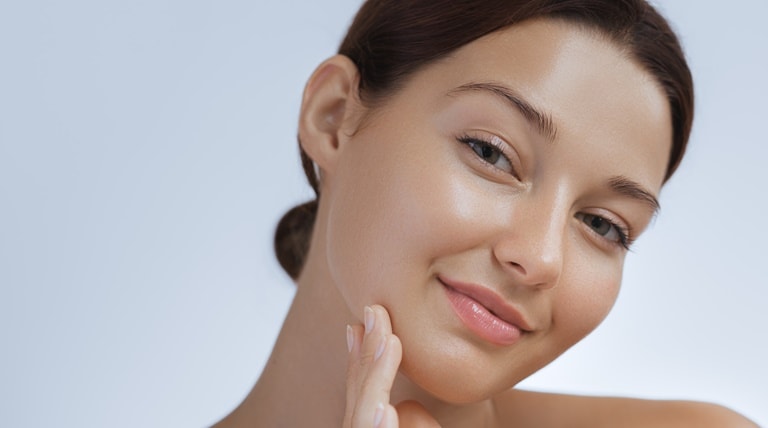 Jovem caucasiana com a pele firme e radiante mostra para que serve a nicotinamida na pele