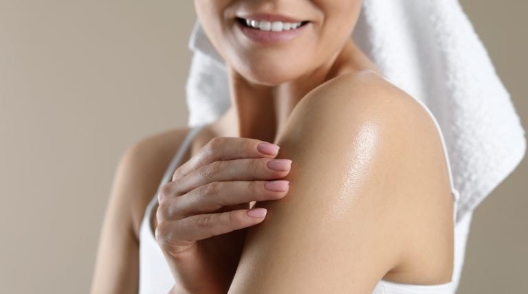 Mulher aplica o óleo corporal e demonstra para que serve na pele