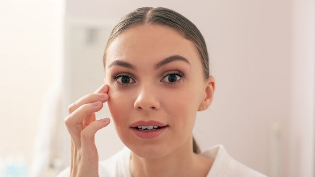 Jovem observa sua pele no espelho com surpresa ao notar os benefícios dos peptídeos na pele