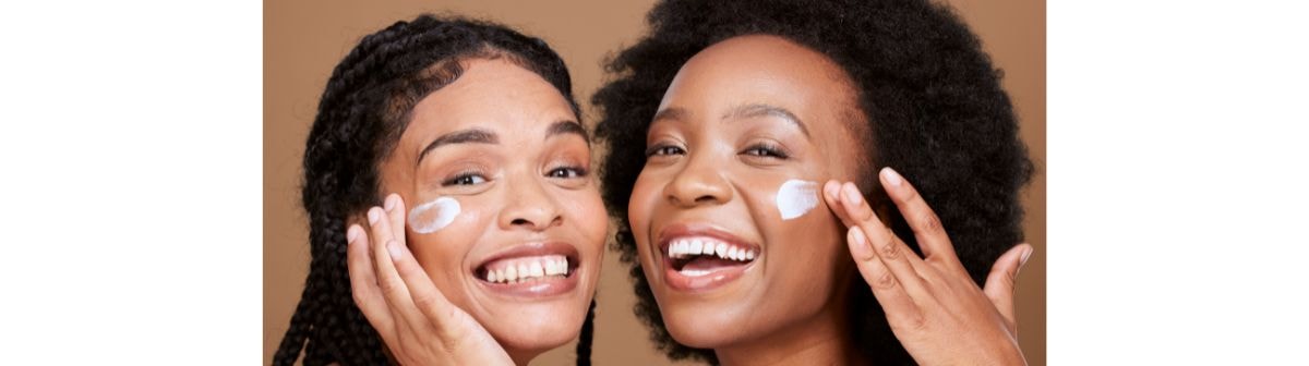 Duas jovens mulheres negras aplicam produtos de skincare em sua pele do rosto