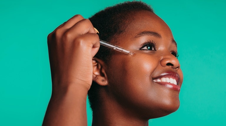 Jovem negra aplica sérum para estimular colágeno no rosto