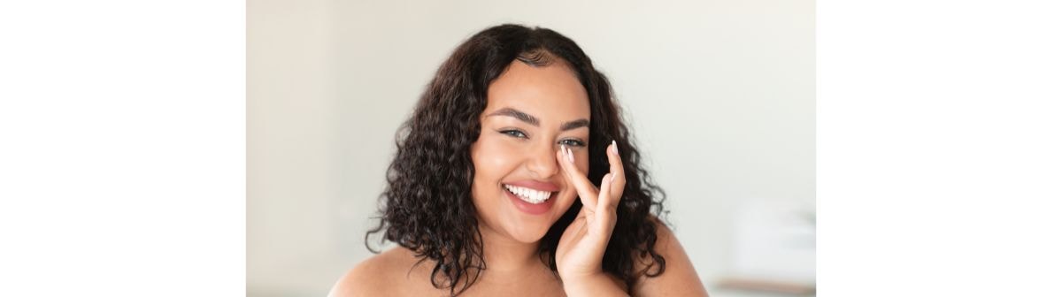 Jovem mulher sorridente usa um hidratante facial combinando colágeno com ácido hialurônico 