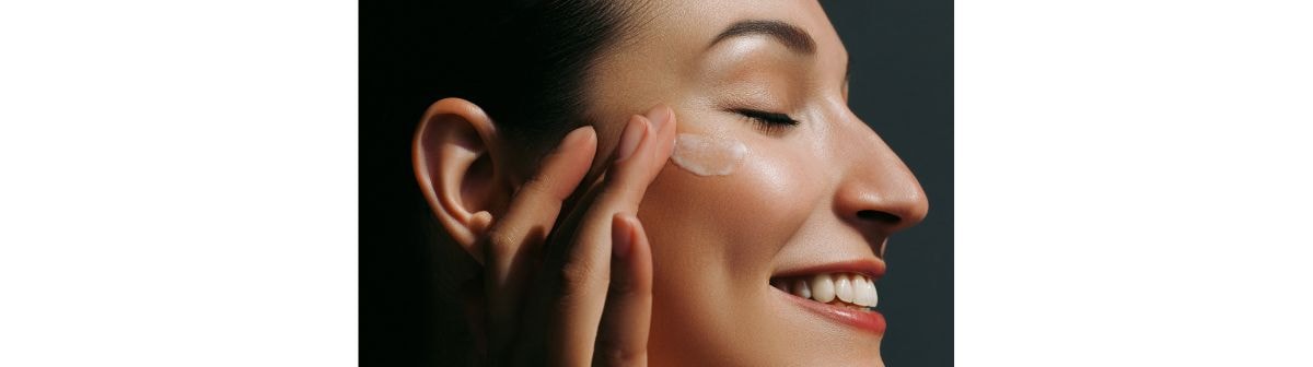 Jovem mulher caucasiana aplica creme hidratante para o rosto em sua pele facial