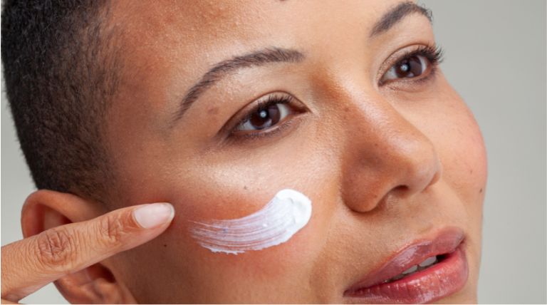 Mulher aplica um creme hidratante para ajudar na prevenção do envelhecimento precoce da pele 