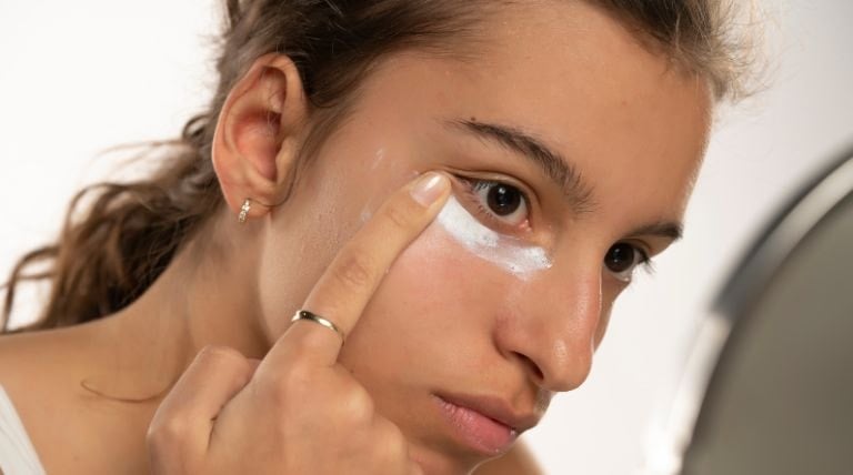 Jovem aplica um hidratante para pele oleosa em seu rosto