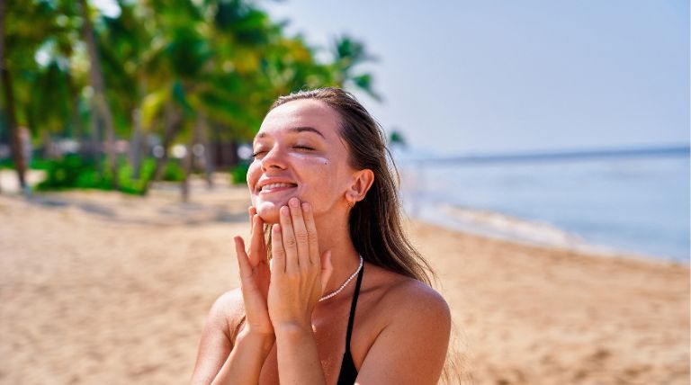 Jovem mulher aplica hidratante para pele oleosa e protetor solar durante o verão